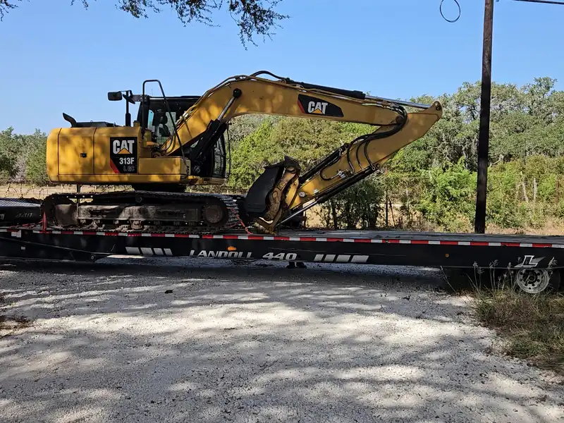 Caliche drive and power pole at the road, with the excavator on its trailer